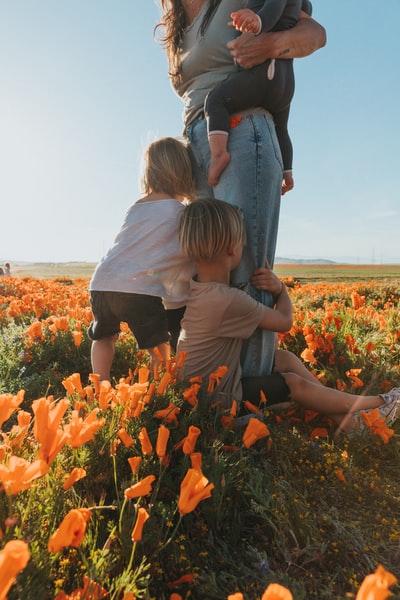 During the day, a woman wearing a white shirt with a girl in a black shirt on the orange flower bed
